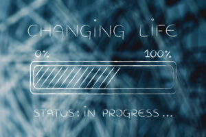 Image of status bar from 0 to 100% half full with the words "Changing Life" above and "Status: In Progress" Underneath